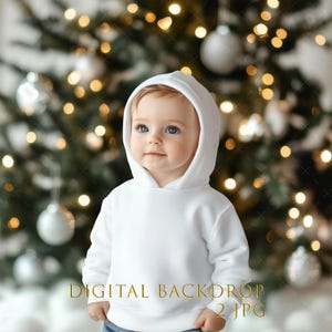 May include: A baby wearing a white hooded sweatshirt, standing in front of a Christmas tree decorated with silver ornaments and twinkling lights. The text "DIGITAL BACKDROP 2 JPG" is at the bottom of the image.