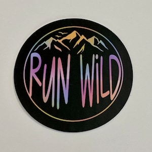 May include: A black and white sticker with a rainbow mountain range design and the text "RUN WILD" in a rainbow font.