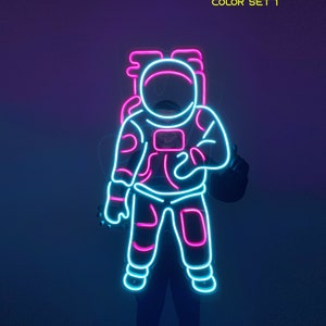 May include: Neon sign of an astronaut in pink and blue. The astronaut is wearing a space suit and has a helmet on. The sign says "COLOR SET 1" at the top.