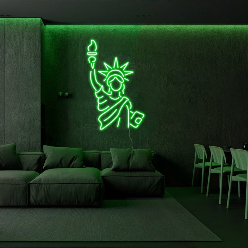 May include: Green neon sign depicting the Statue of Liberty, with a torch in her right hand, on a dark green wall in a living room setting.