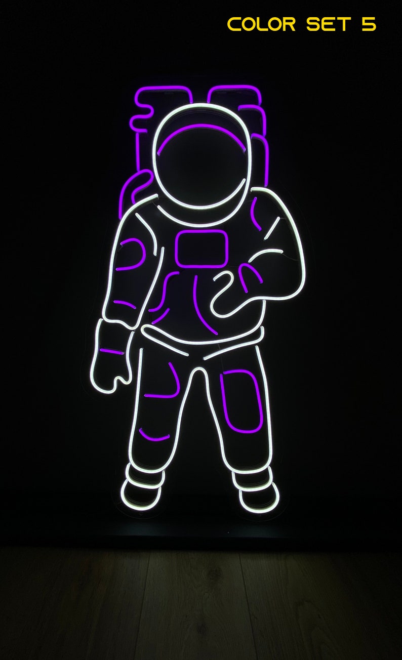 May include: Purple and white neon sign of an astronaut in a space suit. The sign says "COLOR SET 5" at the top.