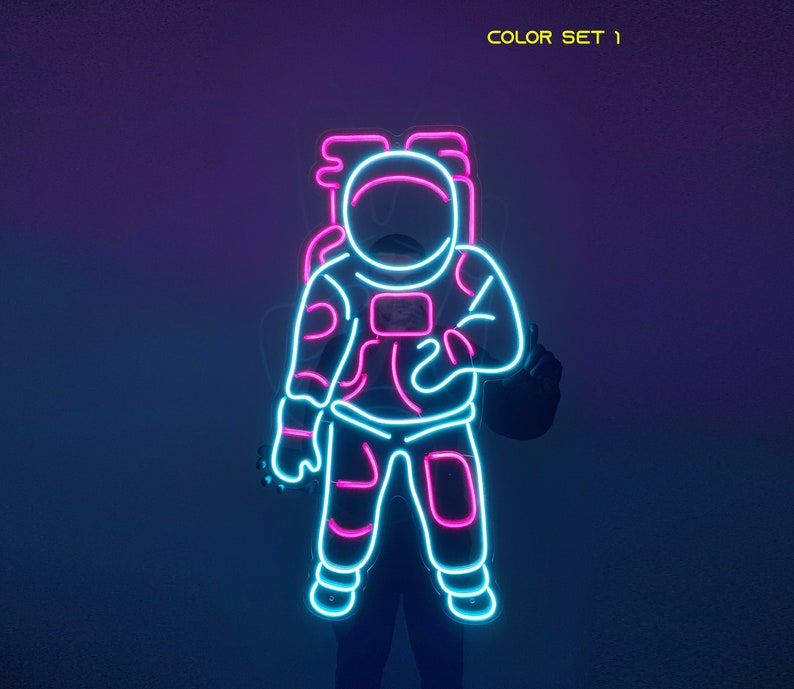 May include: Neon sign of an astronaut in pink and blue. The astronaut is wearing a space suit and has a helmet on. The sign says "COLOR SET 1" at the top.