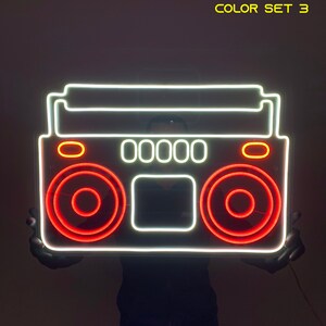 K&ouml;nnte beinhalten: Wei&szlig;er Neon-Umriss eines Boombox mit roten Neon-Akzenten. Der Boombox hat ein Display, das "00000" anzeigt.  COLOR SET 3.