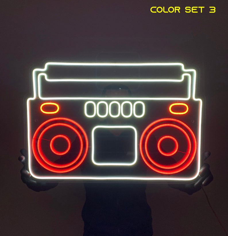 K&ouml;nnte beinhalten: Wei&szlig;er Neon-Umriss eines Boombox mit roten Neon-Akzenten. Der Boombox hat ein Display, das "00000" anzeigt.  COLOR SET 3.