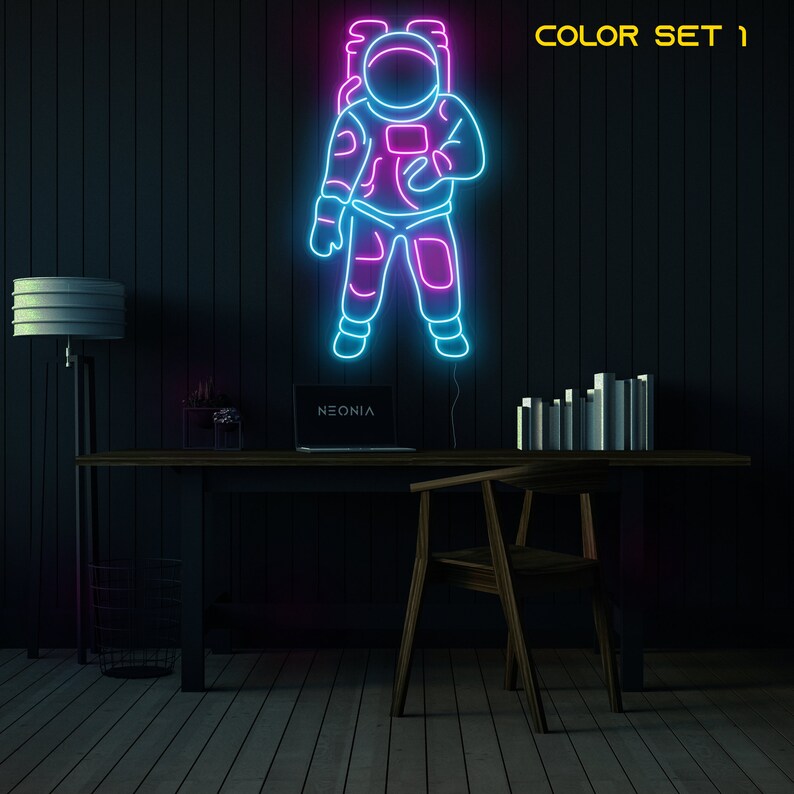 May include: Neon sign of an astronaut in a blue and pink outline against a dark wood background. The sign says "NEONIA" at the bottom. The text "COLOR SET 1" is in the top right corner of the image.