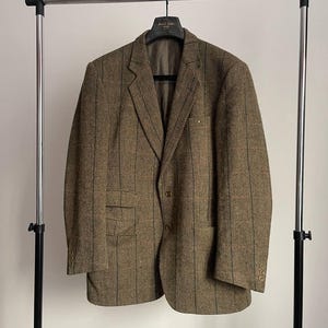 May include: A brown tweed blazer with a striped pattern. The blazer has a single button closure and two flap pockets.