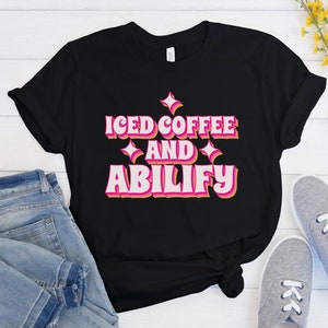 May include: Black t-shirt with a pink and orange graphic that says "Iced Coffee and Ability".