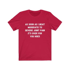 May include: Red t-shirt with white text that reads "AS SOON AS I BEAT MODERATE TO SEVERE JOINT PAIN IT'S OVER FOR YOU HOES"