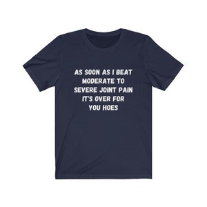May include: Navy blue t-shirt with white text that reads "AS SOON AS I BEAT MODERATE TO SEVERE JOINT PAIN IT'S OVER FOR YOU HOES"