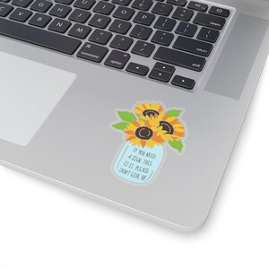 May include: A blue mason jar with a bouquet of yellow sunflowers and green leaves. The jar has the text "If you need a sign, this is it. Please don't give up."