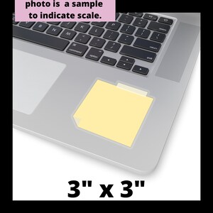 May include: A yellow sticky note with a folded corner, measuring 3 inches by 3 inches, is placed on a silver laptop keyboard.