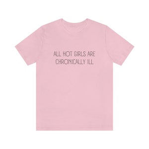 May include: Pink t-shirt with the text "ALL HOT GIRLS ARE CHRONICALLY ILL" printed in black.
