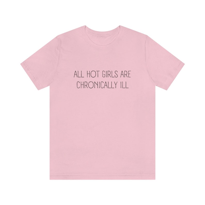 May include: Pink t-shirt with the text "ALL HOT GIRLS ARE CHRONICALLY ILL" printed in black.
