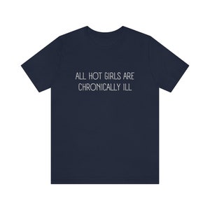 May include: A navy blue t-shirt with the text "ALL HOT GIRLS ARE CHRONICALLY ILL" printed in white on the front.