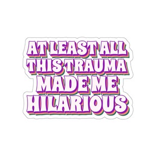 May include: A sticker with the text "At least all this trauma made me hilarious" in a retro font with pink, green, and orange outlines.