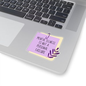 Puede incluir: Una pegatina con una nota adhesiva de color lila claro con el texto "MENTAL ILLNESS IS NOT A PERSONAL FAILURE" en negro. Detr&aacute;s de la nota lila hay una nota adhesiva amarilla y un dise&ntilde;o de hojas moradas en la parte inferior derecha.