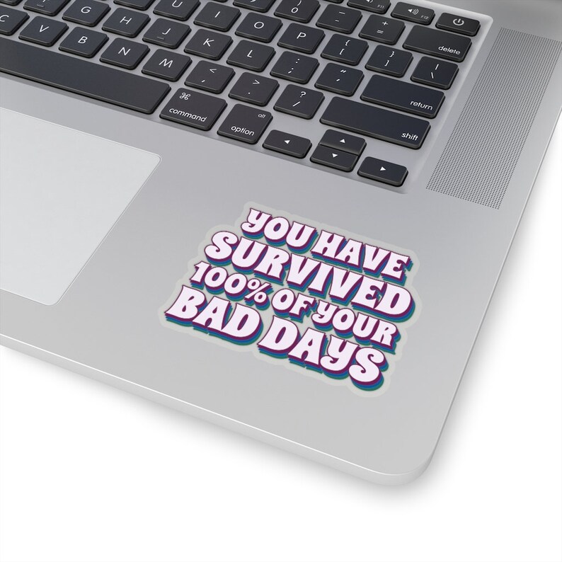 May include: A white sticker with blue and purple text that reads "You Have Survived 100% Of Your Bad Days".