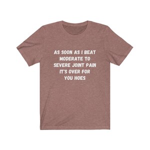May include: A heather brown t-shirt with white text that reads "AS SOON AS I BEAT MODERATE TO SEVERE JOINT PAIN IT'S OVER FOR YOU HOES".