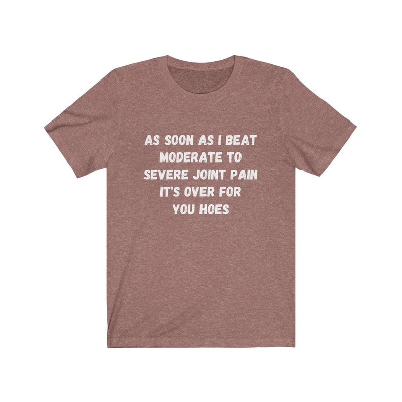 May include: A heather brown t-shirt with white text that reads "AS SOON AS I BEAT MODERATE TO SEVERE JOINT PAIN IT'S OVER FOR YOU HOES".