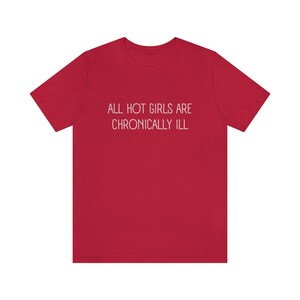 May include: Red t-shirt with the text "ALL HOT GIRLS ARE CHRONICALLY ILL" printed in white.