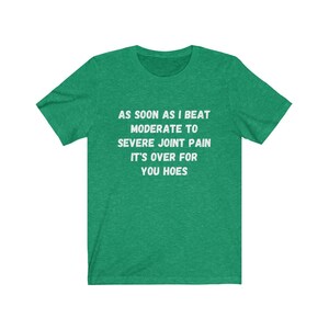 May include: Green t-shirt with white text that reads "AS SOON AS I BEAT MODERATE TO SEVERE JOINT PAIN IT'S OVER FOR YOU HOES"