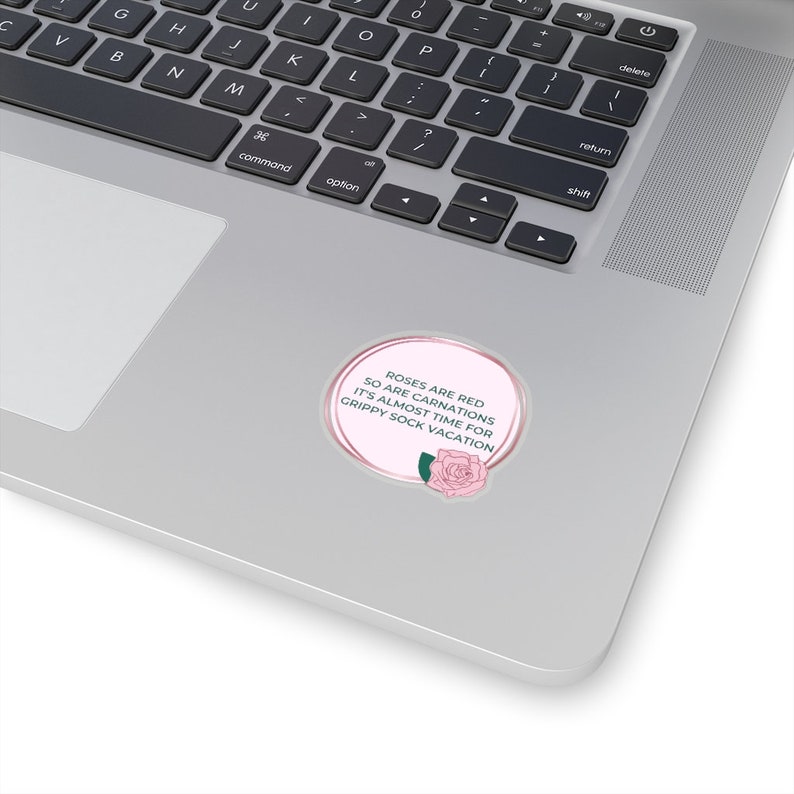 May include: A pink circle sticker with a white outline and a pink rose with green leaves. The text on the sticker reads "Roses are red, so are carnations, it's almost time for grippy sock vacation."