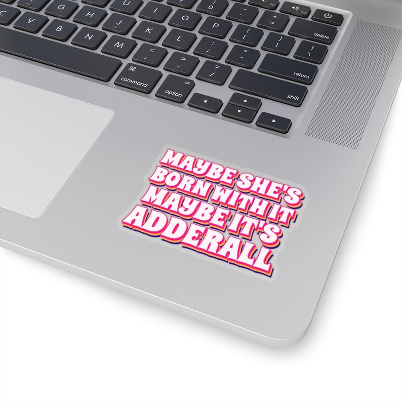 May include: A sticker with the text "Maybe she's born with it maybe it's Adderall" in a retro font style. The text is pink with a yellow outline and a blue shadow.