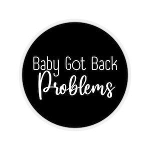 May include: A black and white round sticker with the text "Baby Got Back Problems" in white cursive font.
