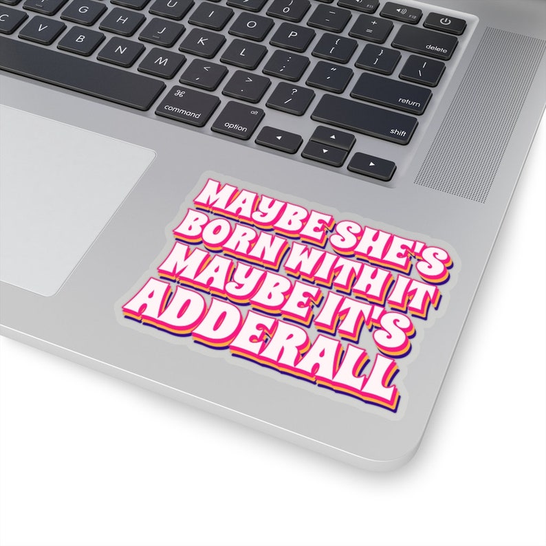 May include: A sticker with the text "Maybe she's born with it maybe it's Adderall" in a retro font style. The text is in pink, yellow, and blue on a white background.