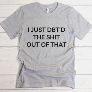 Puede incluir: Una camiseta gris con el texto "I JUST DBT'D THE SHIT OUT OF THAT" impreso en negro.