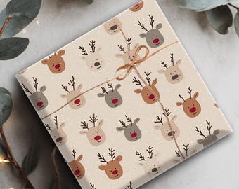 May include: A wrapped gift with beige paper featuring a pattern of reindeer faces in brown, gray, and white. The gift is tied with twine and decorated with a sprig of eucalyptus.