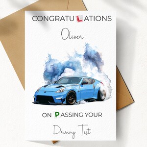 Peut inclure: Carte de félicitations pour l'obtention du permis de conduire avec une illustration de voiture de sport bleue. Le texte dit : "Félicitations Oliver pour avoir réussi votre permis de conduire".