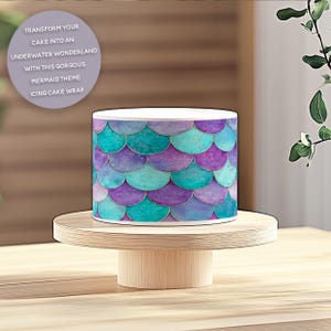May include: A mermaid-themed icing cake wrap with a teal, purple, and white design. The cake wrap features a scale pattern and the text: TRANSFORM YOUR CAKE INTO AN UNDERWATER WONDERLAND WITH THIS GORGOUS MERMAID THEME ICING CAKE WRAP.