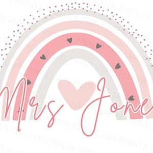 May include: A pastel rainbow design with the text "Mrs Jones" in a cursive font. The rainbow features shades of pink, grey, and white, with small grey hearts and pink polka dots.