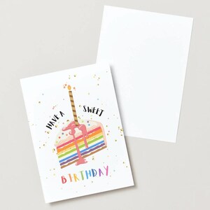 May include: A white greeting card with a watercolor illustration of a rainbow cake slice with a lit candle. The card reads "Have a Sweet Birthday" in colorful text. A blank white card is next to it.