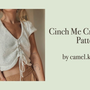 May include: A white knit crop top with a cinched detail at the front. The top has a V-neck and short sleeves. The text "Cinch Me Crop Pattern by camel.knits" is visible in the image.