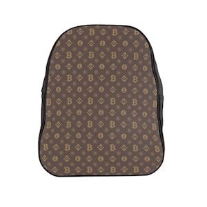 Könnte beinhalten: Ein brauner Lederrucksack mit schwarzem Besatz. Der Rucksack hat ein sich wiederholendes Muster aus goldenen Bitcoin- und Litecoin-Symbolen.