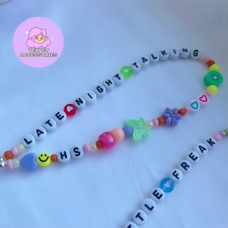 May include: A colorful beaded necklace with the words "Late Night Talking" and "Little Freak" spelled out. The necklace also features a butterfly charm, a flower charm, and a smiley face charm.