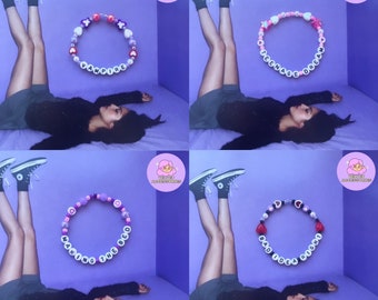 May include: Four different beaded bracelets with colorful beads and letters spelling out "Vampire", "Teenage Dream", "Making the Bed", and "Bad Idea Right".
