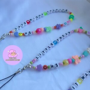 May include: A colorful beaded phone charm with the words "Late Night Talking" and "Little Freak" on it. The charm also features a butterfly, hearts, and smiley faces.