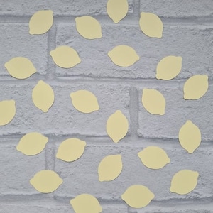 May include: A white brick wall background with yellow lemon-shaped confetti scattered across the surface.