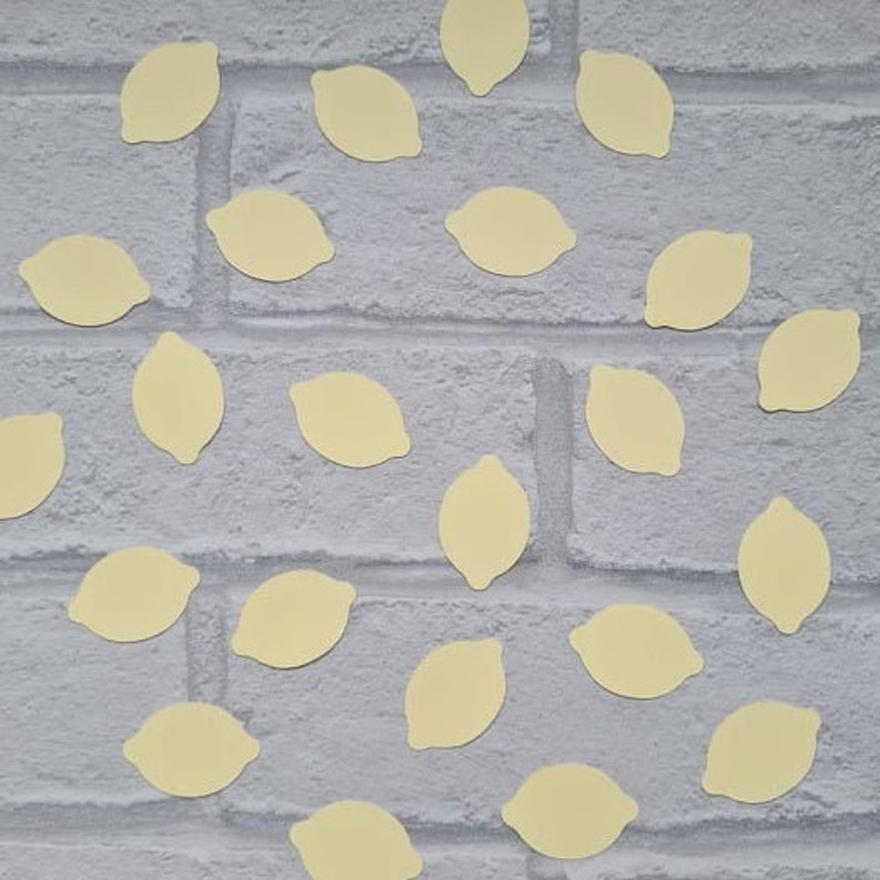 May include: A white brick wall background with yellow lemon-shaped confetti scattered across the surface.