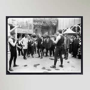 Könnte beinhalten: Ein Schwarzweißfoto einer Gruppe von Männern, von denen einige boxen. Ein Mann hält einen Boxsack, während ein anderer Mann einen Boxhandschuh hält. Die Männer stehen vor einem Gebäude mit der Aufschrift "The Gallery" an der Seite.