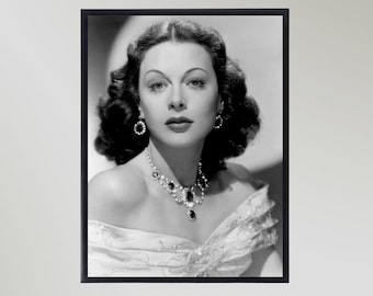 May include: Black and white portrait photograph of a woman with dark, wavy hair. She is wearing a white dress and a large, jeweled necklace.