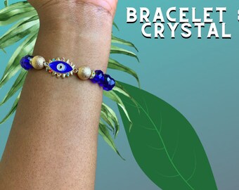 May include: A blue and gold bracelet with an evil eye charm. The bracelet is made with blue glass beads and gold accents. The evil eye charm is a popular symbol of protection and good luck.