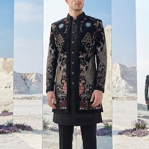Op de afbeelding: Een zwarte geborduurde jas met een opstaande kraag, gedragen over een zwarte tuniek en broek. De jas heeft gedetailleerde bloemen- en vogelontwerpen in goud-, rood- en blauwtinten. De outfit wordt gecompleteerd met zwarte schoenen.