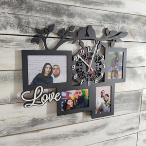 Puede incluir: Reloj de pared negro con marcos de fotos y un diseño de rama decorativa. El reloj presenta una esfera recortada, un segundero rojo y la palabra "Love" en escritura blanca. El reloj tiene cuatro marcos de fotos.