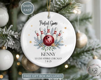 May include: A white ceramic Christmas ornament with a bowling theme. The ornament features a red bowling ball and pins, with the text "Perfect Game" and the name "Kenny". The ornament is decorated with gold stars and greenery.