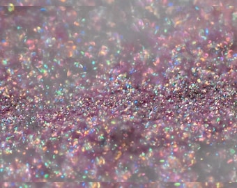 May include: Close-up of a shimmering, glittery surface. The glitter is primarily a soft purple color, with iridescent flecks that catch the light, creating a sparkling effect. The overall texture is dense and visually appealing, suggesting a decorative or craft material.