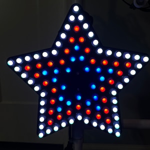 May include: A star-shaped light fixture with white, red, and blue LED lights. The lights are arranged in a circular pattern.